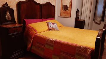 Un dormitorio con cama de madera, una mesita de noche, un aparador, un espejo y un radiador.