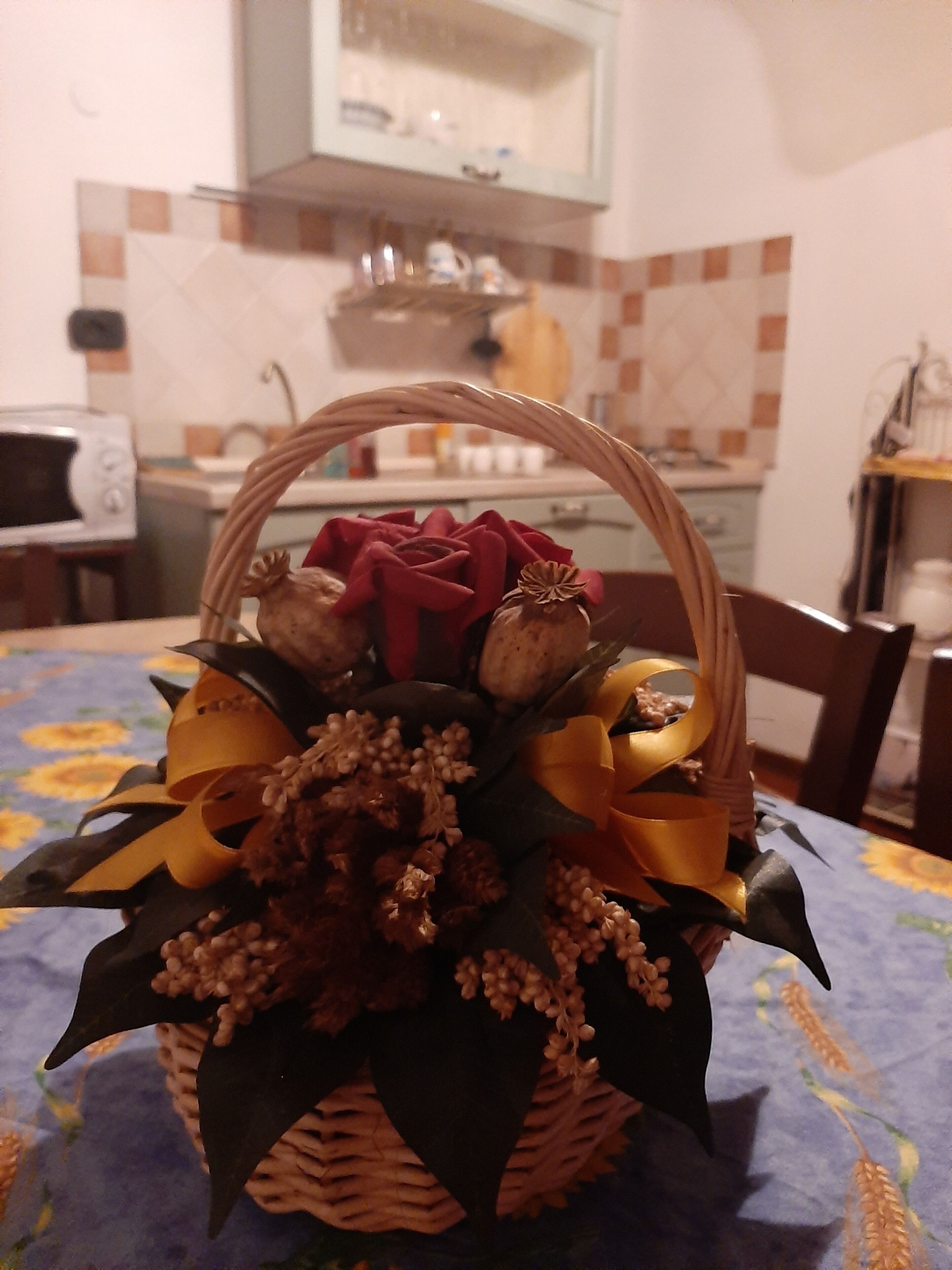 Ein Korbwägelchen mit einem Blumenarrangement auf einer Tischplatte.