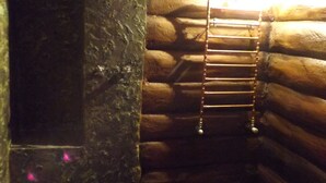 A rustic log cabin interior with a stone wall, a wooden ladder, and a wooden bench. - B&B Pervinca (Rocca Grimalda)