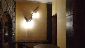 Una habitación con pared de piedra, una mesa redonda y una lámpara.