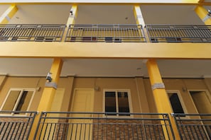 A multi-story building with yellow walls and a balcony with metal railings. - RedDoorz Plus near Palembang Square Mall (Palembang)