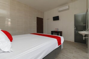 A hotel room with a bed, a bedside table, a TV, and a bathroom with a sink. - RedDoorz Plus near RS Royal Prima (Medan)