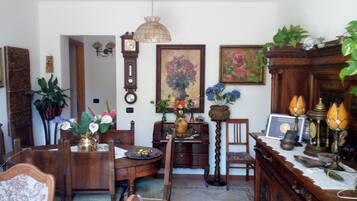 A traditional dining room with wooden furniture, a chandelier, and various decorative items including a clock and paintings.