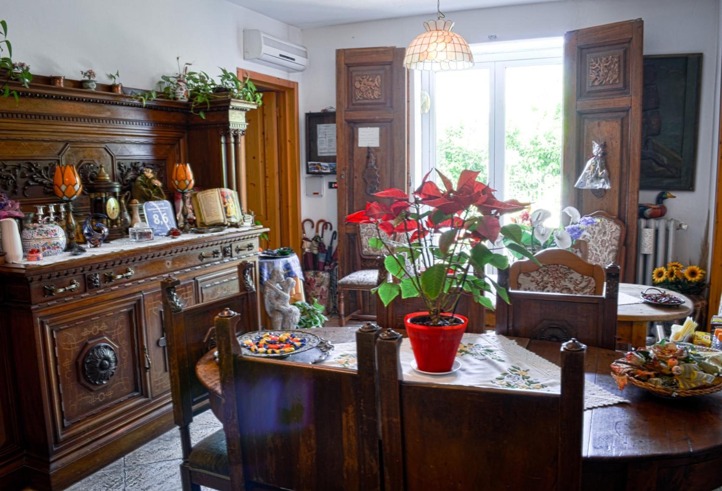 Un comedor tradicional con una mesa de madera, sillas y una planta en maceta roja.