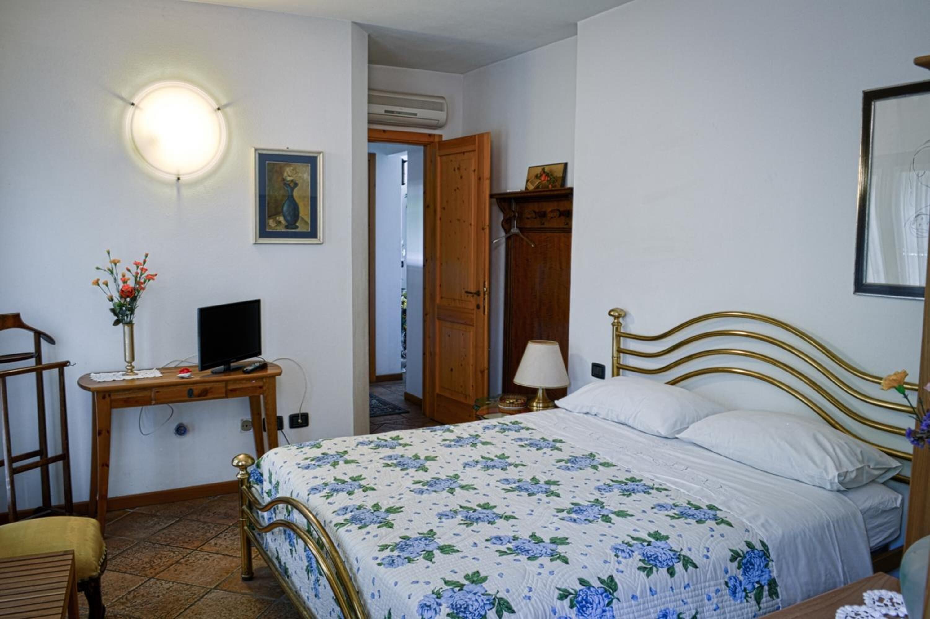 Une chambre à coucher comprenant un lit, une table de chevet, une lampe et un téléviseur fixé au mur.