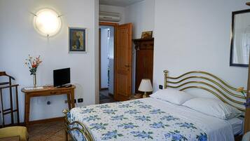 Une chambre à coucher comprenant un lit, une table de chevet, une lampe et un téléviseur fixé au mur.