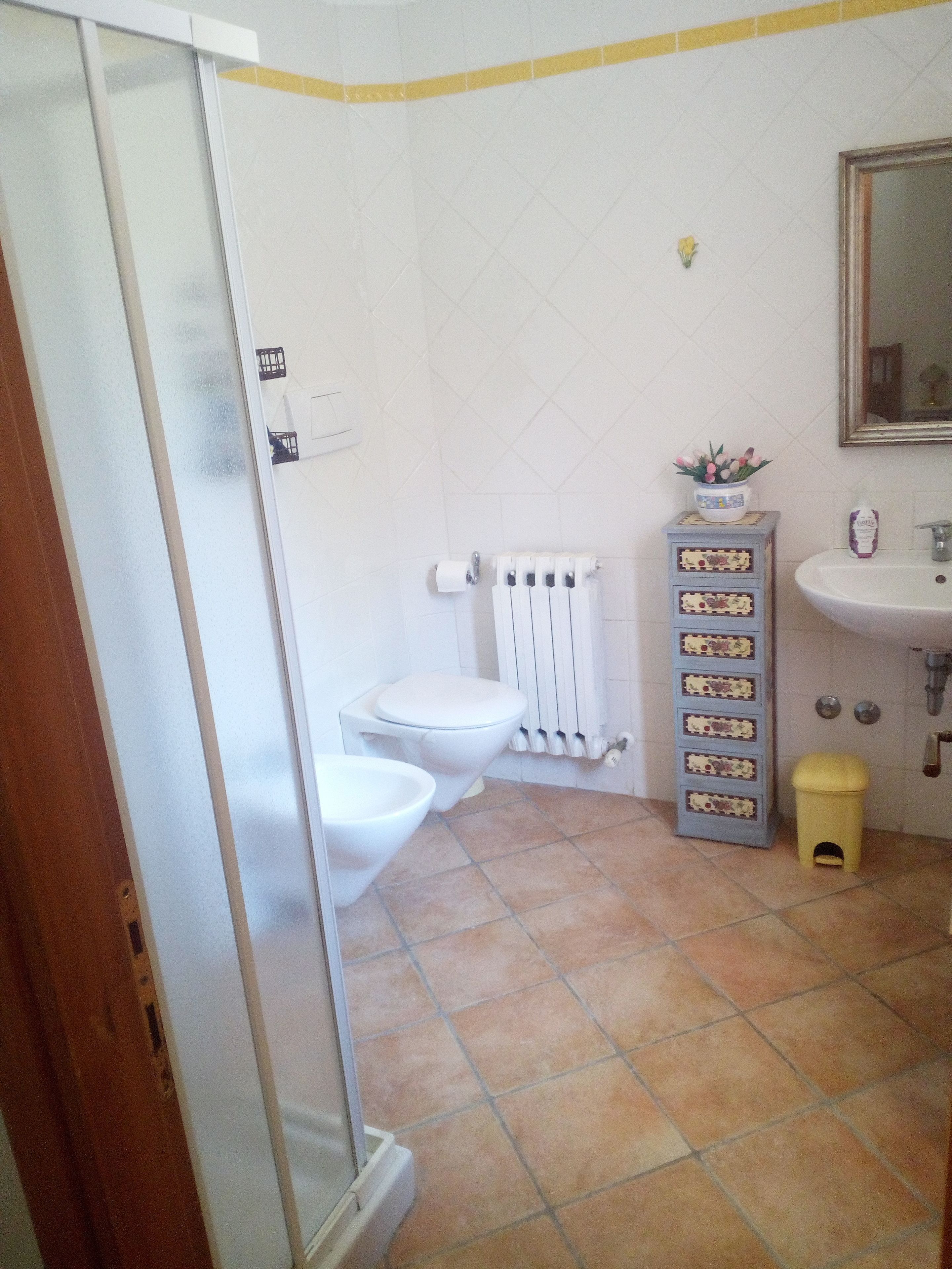 Baño con inodoro, bidé y un pequeño cubo de basura.