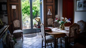 A dining area with a wooden table, patterned chairs, and a vase with flowers.