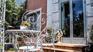 A patio with a metal table and chairs, a statue, and a building entrance with a glass door.