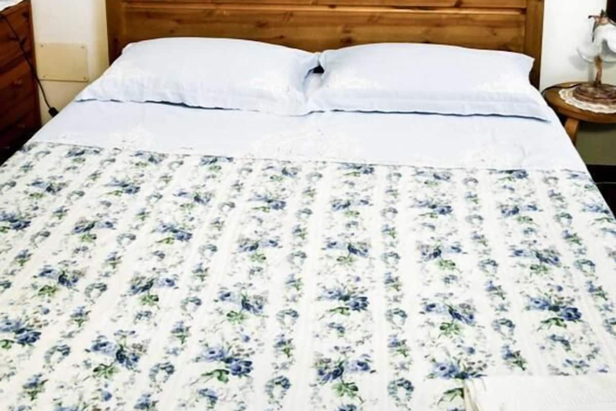 Een slaapkamer met een houten hoofdeinde, een bloemenbedovertrek en twee ingelijste kunstwerken aan de muur.
