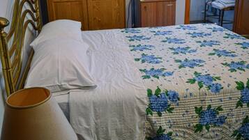 Un dormitorio con cama, armario de madera, espejo, lámpara y una mesita con bandeja.
