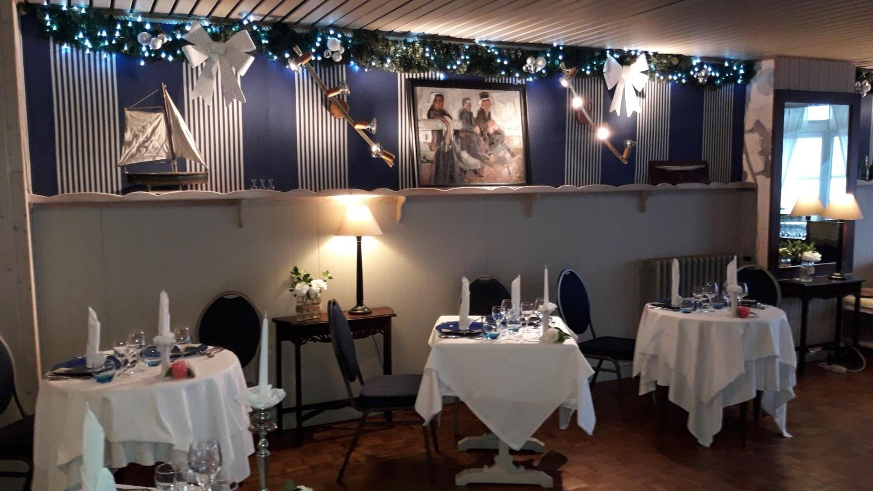 Un comedor con mesas dispuestas para una comida, con papel tapiz a rayas y decoración festiva.