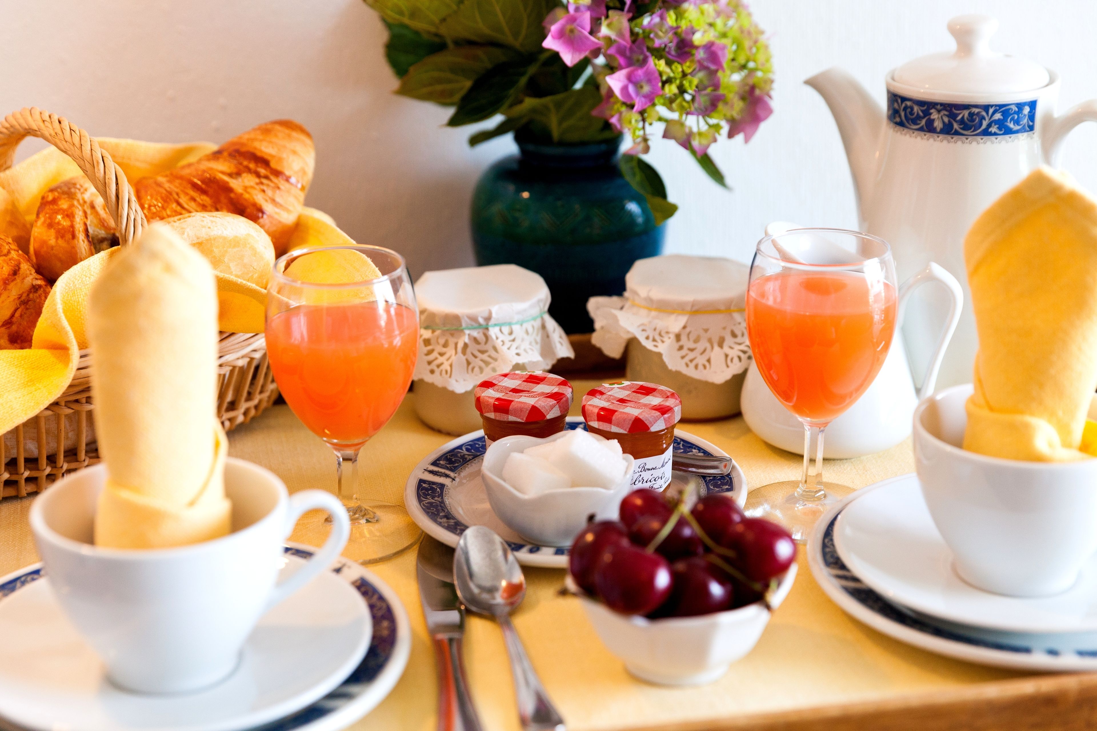 A breakfast setting with croissants, fruit, and beverages on a table.