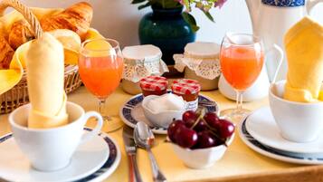 A breakfast setting with croissants, fruit, and beverages on a table.