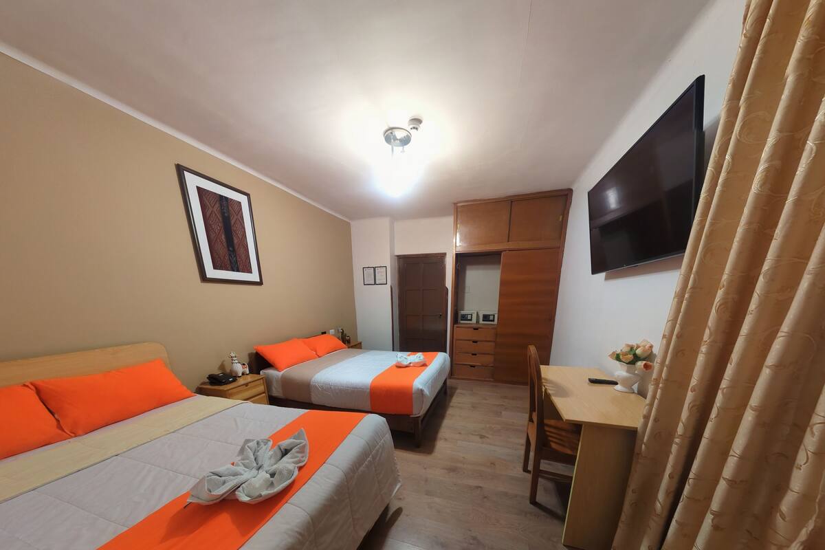 A hotel room with two beds, a desk, a TV, and a wardrobe.