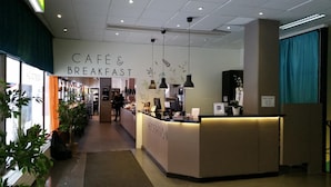 A café and breakfast area with a reception desk, plants, and a counter. - Vandrarhem Uppsala Centralstation - Hostel (Uppsala)