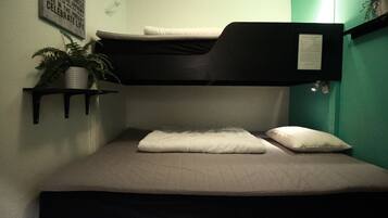 A bunk bed with a mattress and pillows, a small shelf with a plant, and a wall with a framed inspirational quote.
