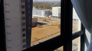 Vista desde una ventana sobre un estacionamiento y edificios, con cielo despejado.