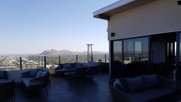 Terraza en la azotea con mobiliario exterior y vista panorámica de la ciudad.