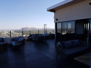 Terraza en la azotea con mobiliario exterior y vista panorámica de la ciudad.
