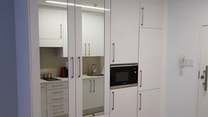 Cocina moderna con armarios blancos, microondas y pileta.