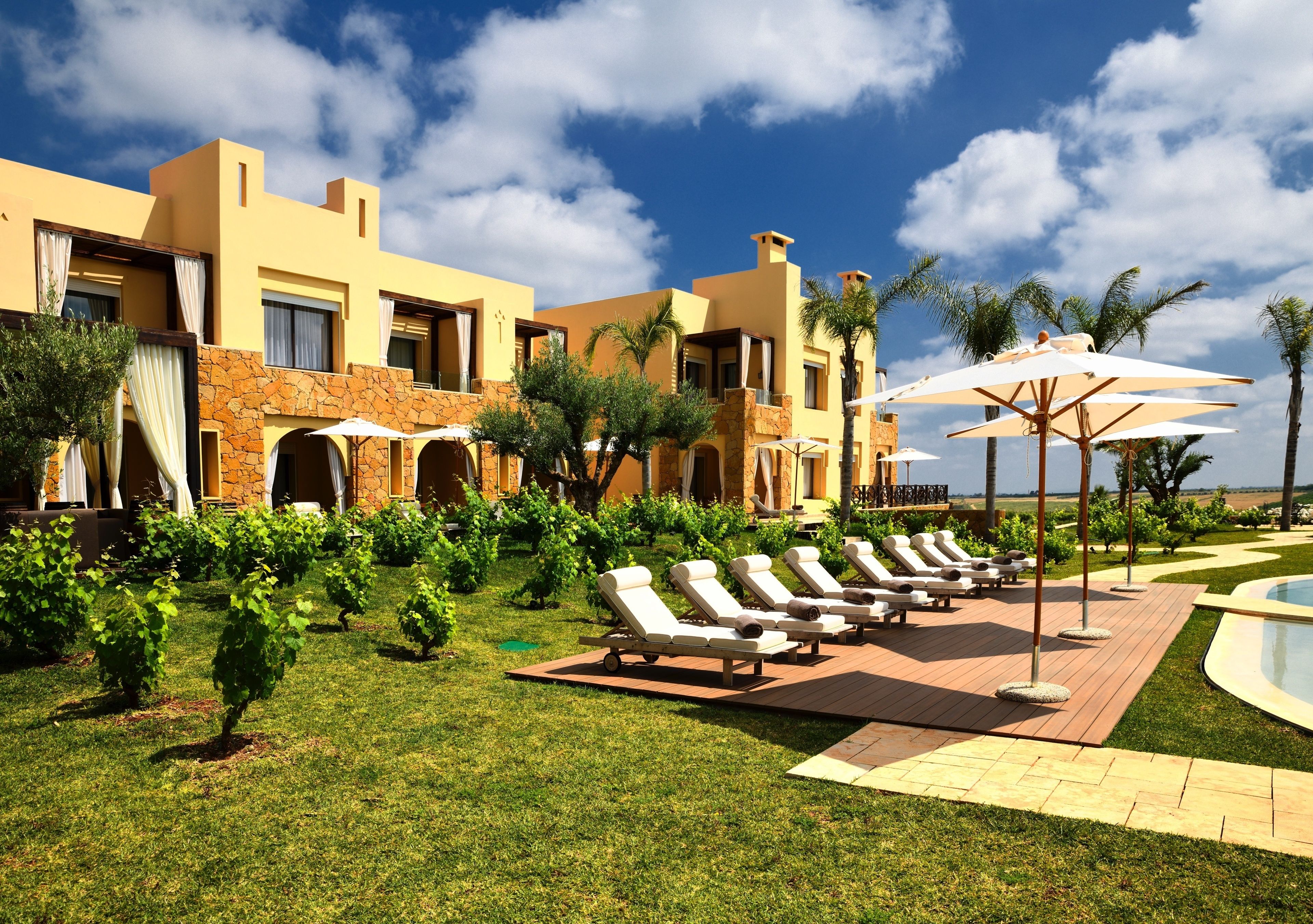 Um resort com piscina, espreguiçadeiras e um jardim bem cuidado.