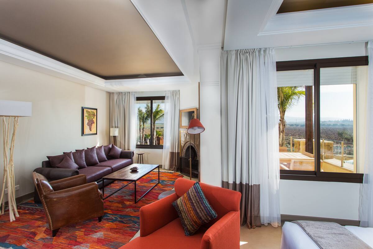 Una sala de estar moderna con un sofá, sillones, una chimenea y un ventanal con vistas.