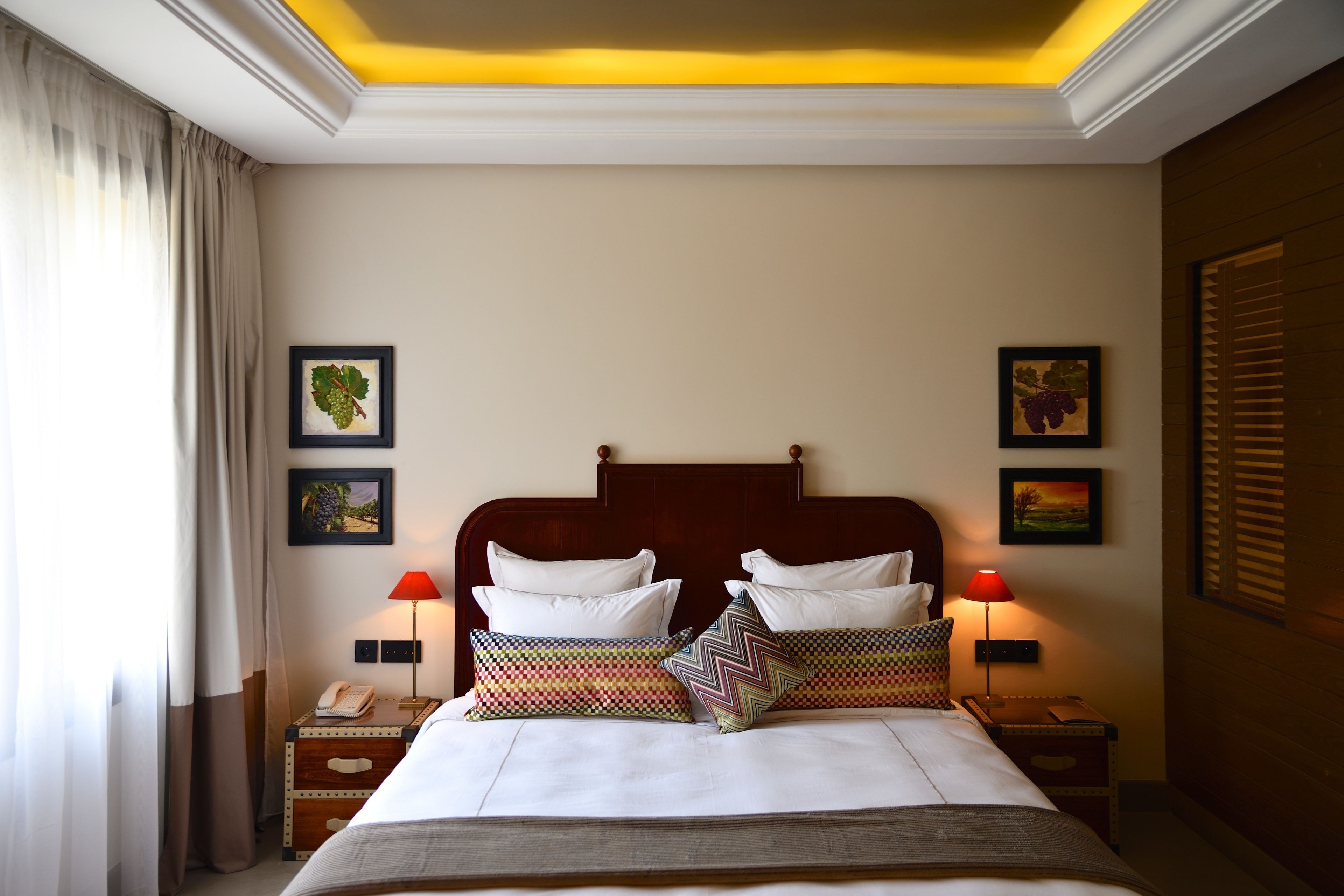 A hotel room with a large bed, two bedside tables, a nightstand, and a ceiling light.