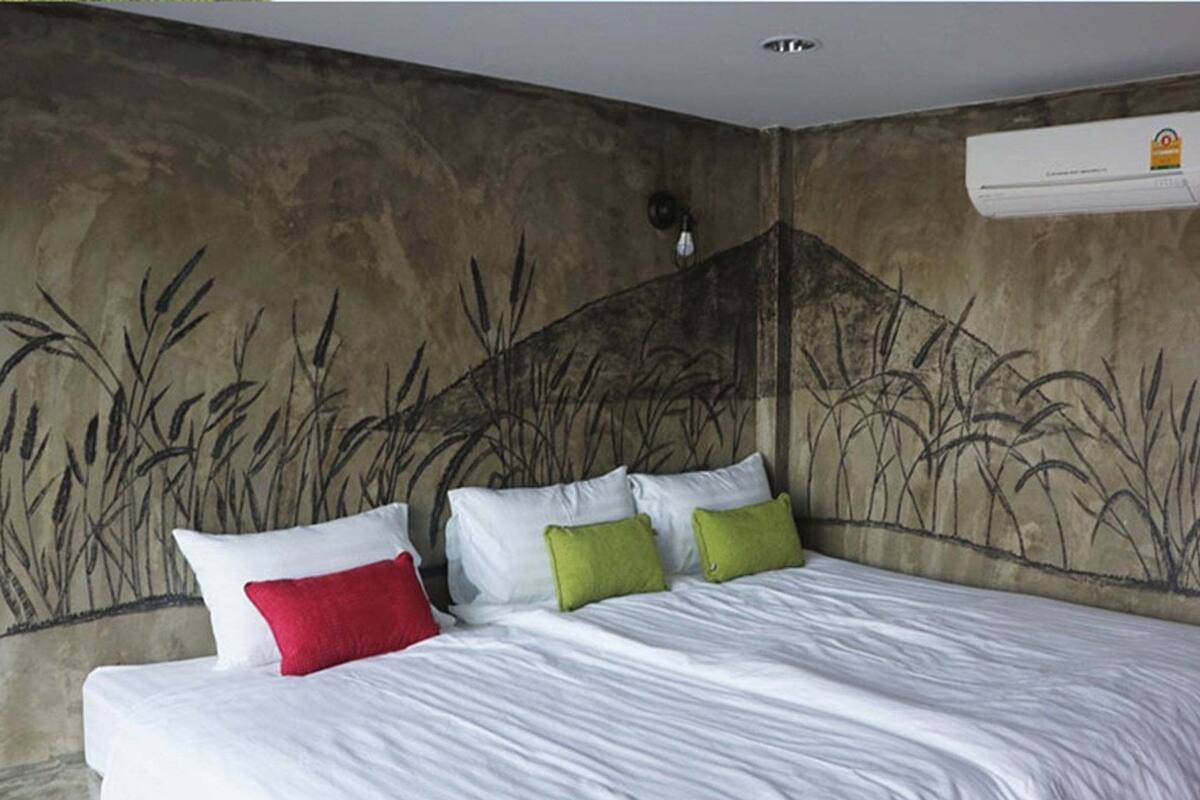 A bedroom with a bed, pillows, and a wall mural.