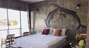 A bedroom with a large bed, a view through a window, and a wall mural.