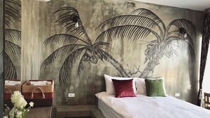 Quarto com cama, almofadas e um mural na parede com palmeiras.