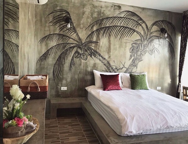 A bedroom with a bed, pillows, and a wall mural of palm trees.