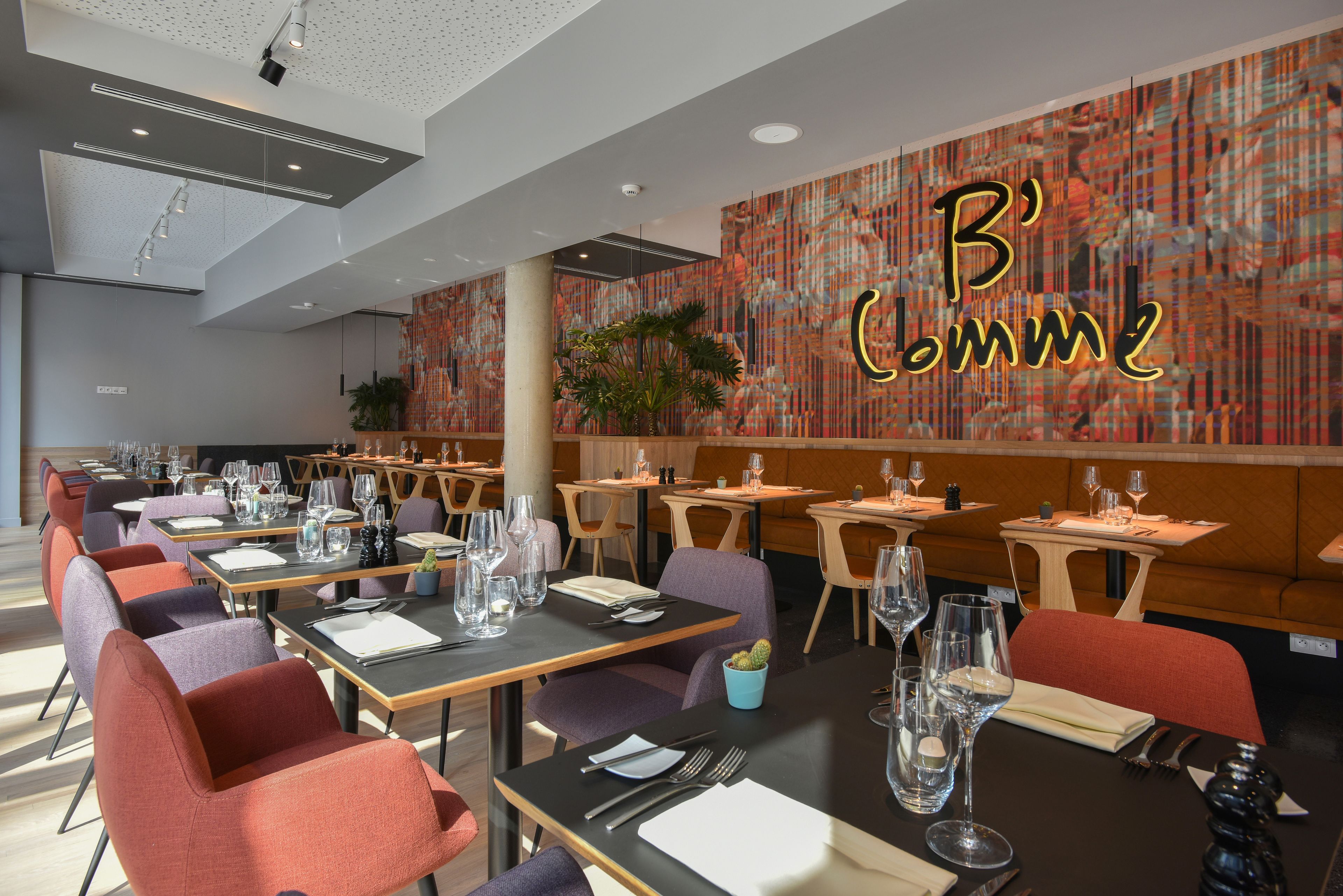 Un restaurante moderno con varias mesas de comedor, cada una dispuesta con cubiertos y copas.