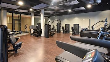 Un gimnasio con diverso equipo de ejercicio, incluyendo cintas de correr y máquinas de pesas.