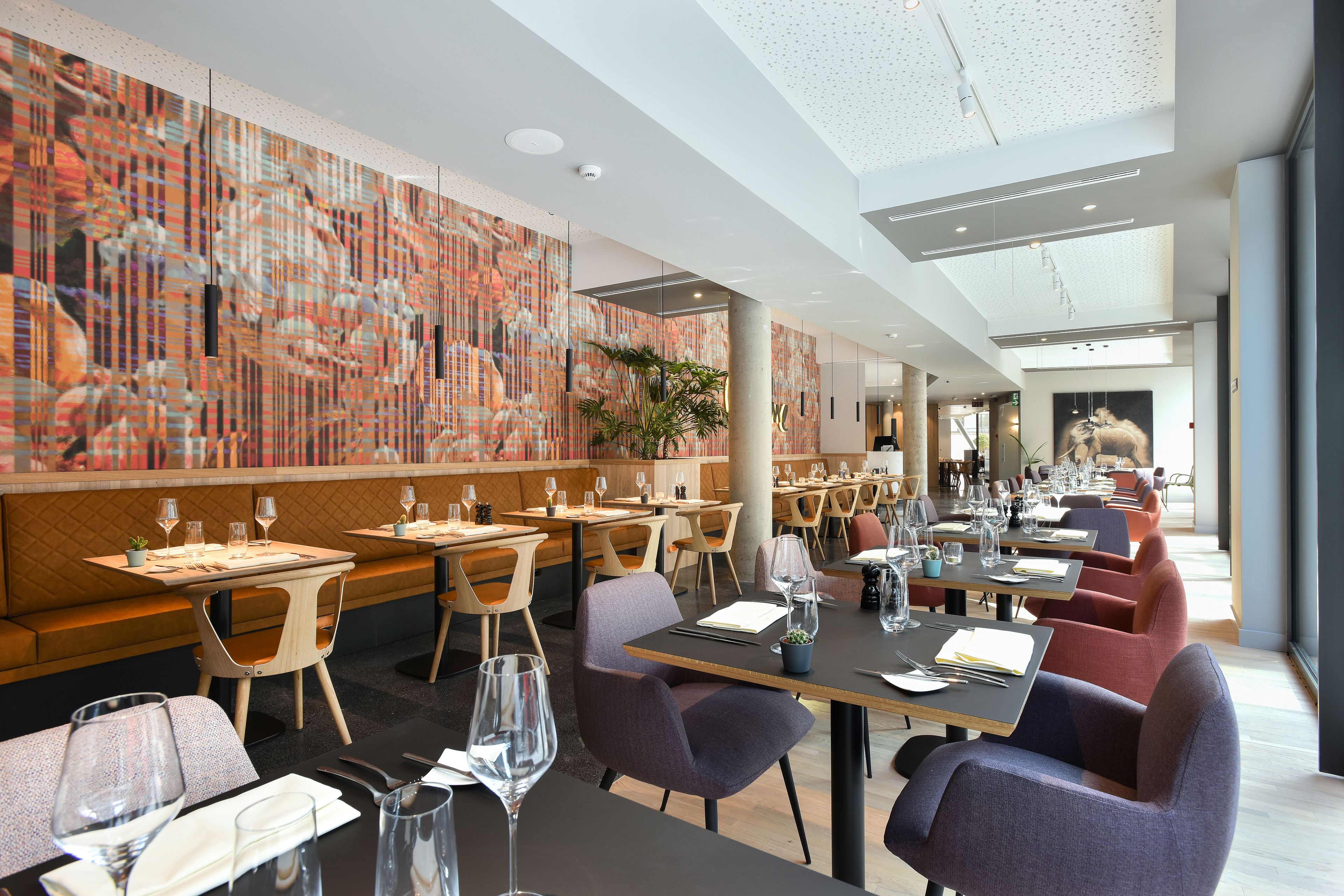 A modern restaurant with a long counter, booths, and a high ceiling with a skylight.