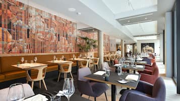 A modern restaurant with a long counter, booths, and a high ceiling with a skylight.