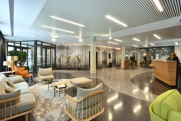 A spacious lobby with modern furniture, a reception desk, and potted plants. - Martin's Louvain-la-Neuve (Ottignies-Louvain-la-Neuve)