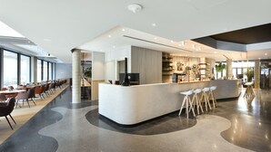Un espace bar moderne doté d’un comptoir incurvé, de sièges et d’un bar bien visible où sont exposées les bouteilles.