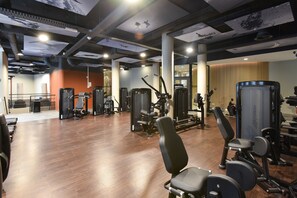 A gym with various exercise machines, wooden flooring, and a modern ceiling design. - Martin's All Suites (Ottignies-Louvain-la-Neuve)