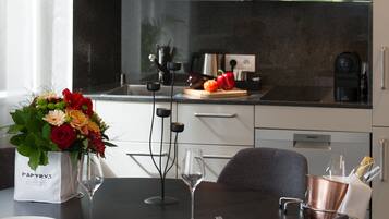 Una cocina moderna con comedor, que presenta un comedor negro, sillas grises y un ramo de flores sobre la mesa.