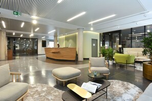 A modern lobby with a reception desk, seating area, and large windows. - Martin's All Suites (Ottignies-Louvain-la-Neuve)