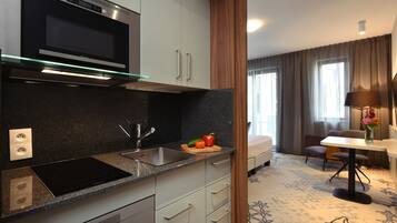 A modern kitchen with a built-in microwave, stainless steel sink, and a cutting board with vegetables.