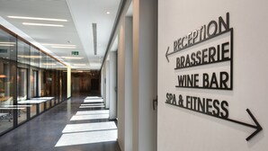 A modern hotel corridor with directional signs for Reception, Brasserie, Wine Bar, and Spa & Fitness. - Martin's All Suites (Ottignies-Louvain-la-Neuve)