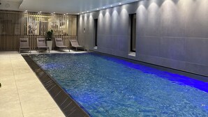 An indoor swimming pool with a modern design, including a patterned ceiling and recessed lighting. - Martin's All Suites (Ottignies-Louvain-la-Neuve)