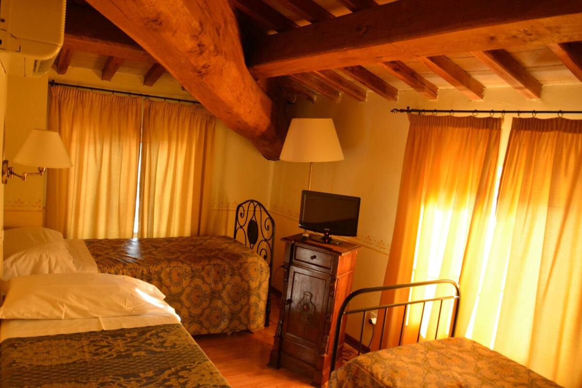 Un dormitorio con dos camas, un aparador de madera, un televisor y cortinas.