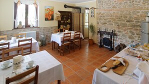 A dining area with multiple tables and chairs, a stone wall, and a fireplace. - B&B La Fenice (Mondaino)