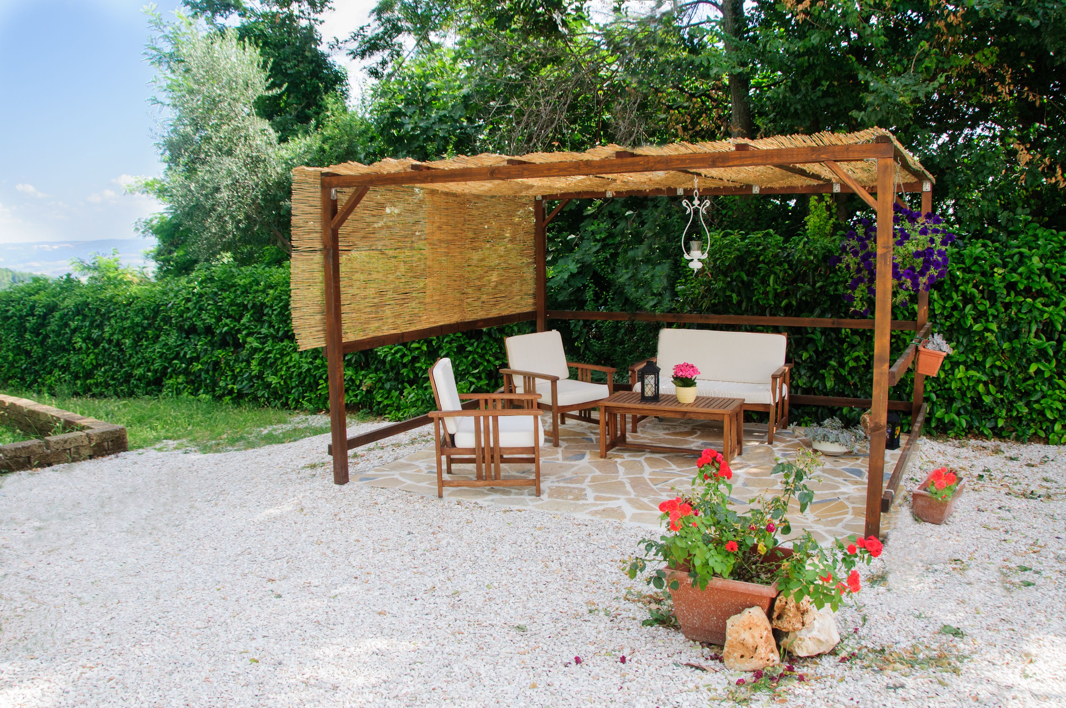 Una pérgola de madera con una mesa y sillas en un jardín.