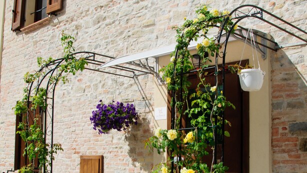 A stone building with a rustic charm, featuring a wooden door and shuttered windows. - B&B La Fenice (Mondaino)