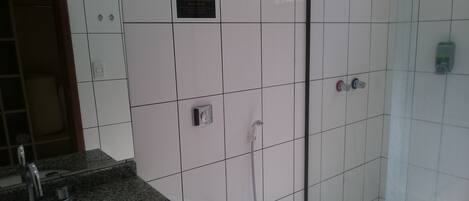 A bathroom with a granite countertop sink, a glass shower enclosure, and a white toilet.