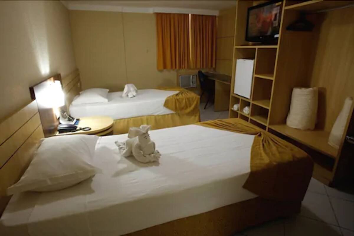 A hotel room with two beds, a desk, a television, and a wardrobe.